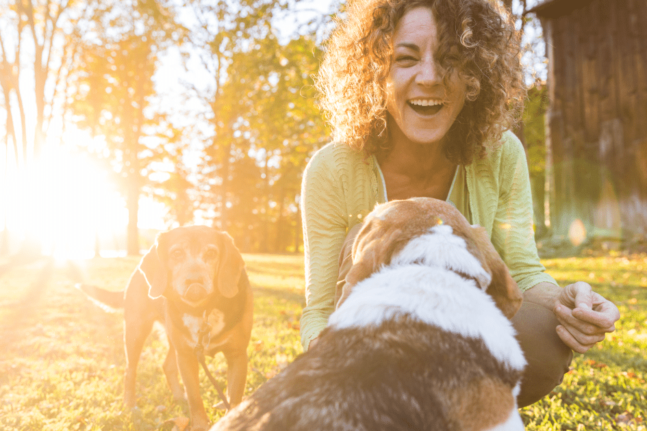 Lady playing joyfully with her two dogs outside in the daylight, symbolizing heart health and happiness in menopause.