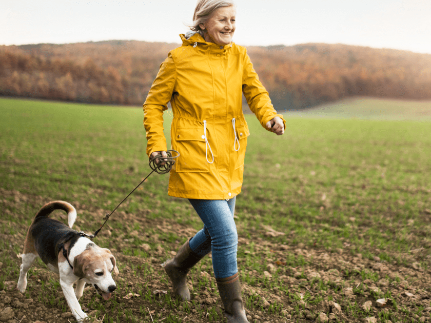 Pets and Wellness: Senior woman walking her dog on a sunny day, illustrating the positive impact of animals on our well-being.