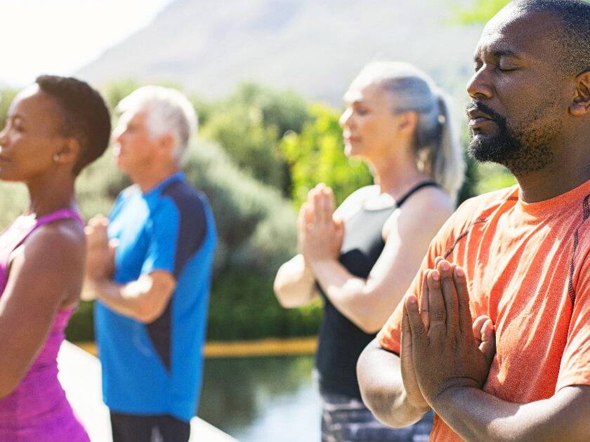 Group practicing breath-focused meditation outdoors for blood pressure control, embodying tranquility and collective wellness in serene weather.