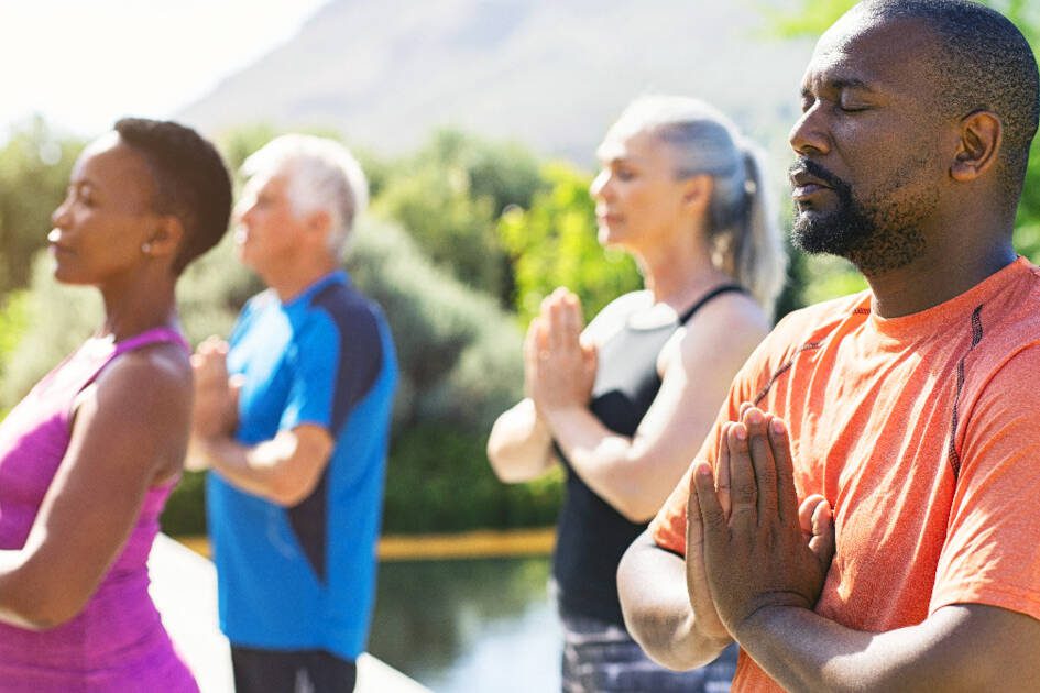 Group practicing breath-focused meditation outdoors for blood pressure control, embodying tranquility and collective wellness in serene weather.