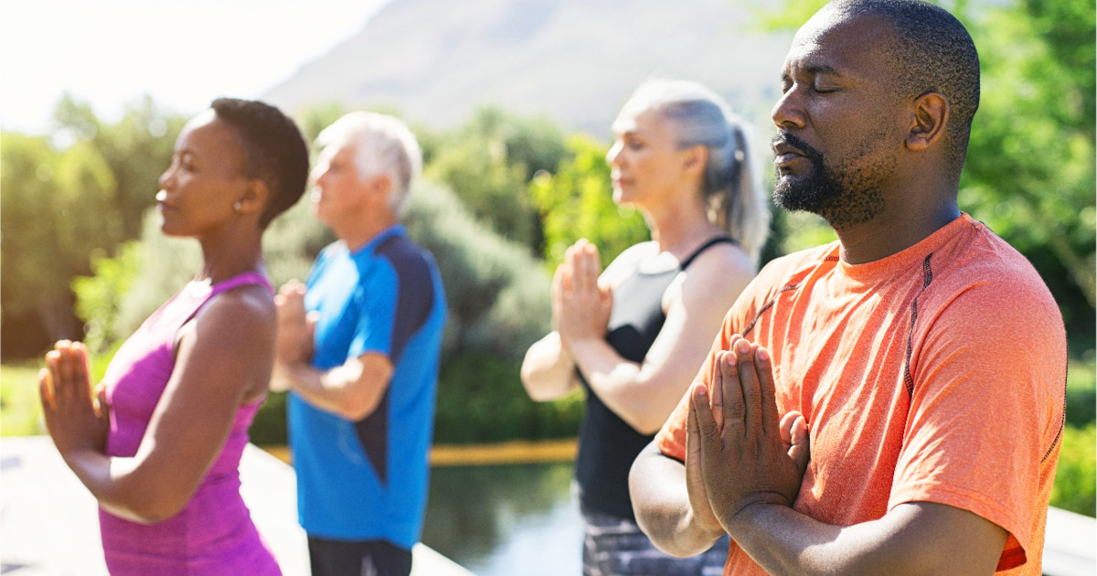 Group practicing breath-focused meditation outdoors for blood pressure control, embodying tranquility and collective wellness in serene weather.