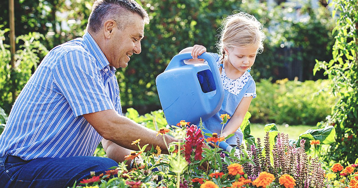 Heart Health Supplement - A father and daughter watering plants together outdoors, symbolizing healthy lifestyle choices.