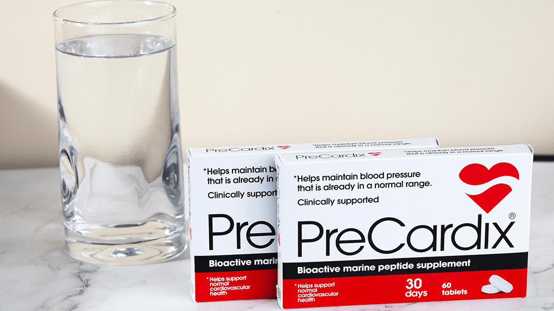 Heart Hydration: A PreCardix® package box next to a clear glass of water, placed on a marble table indoors.