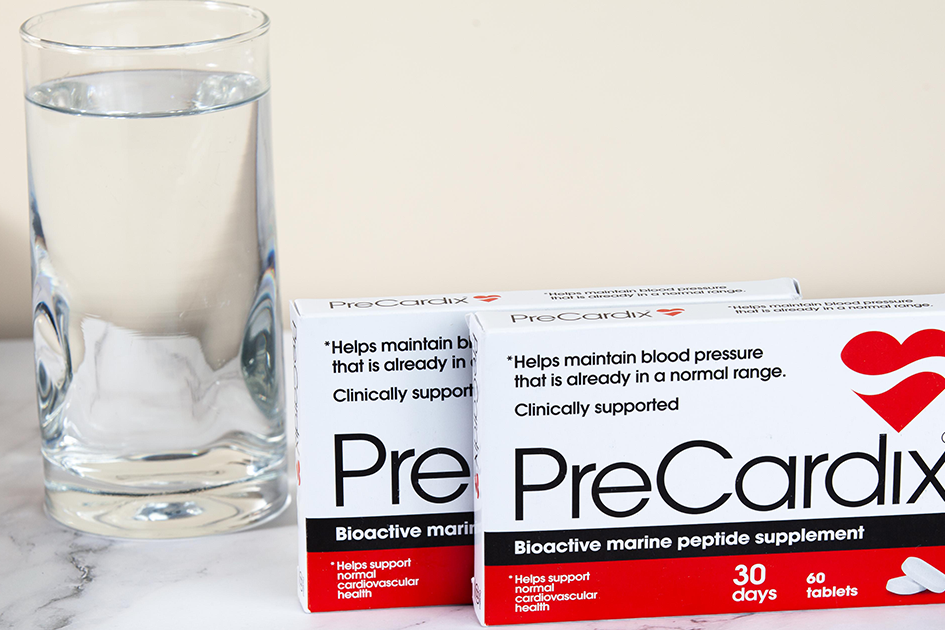 Heart Hydration: A PreCardix® package box next to a clear glass of water, placed on a marble table indoors.