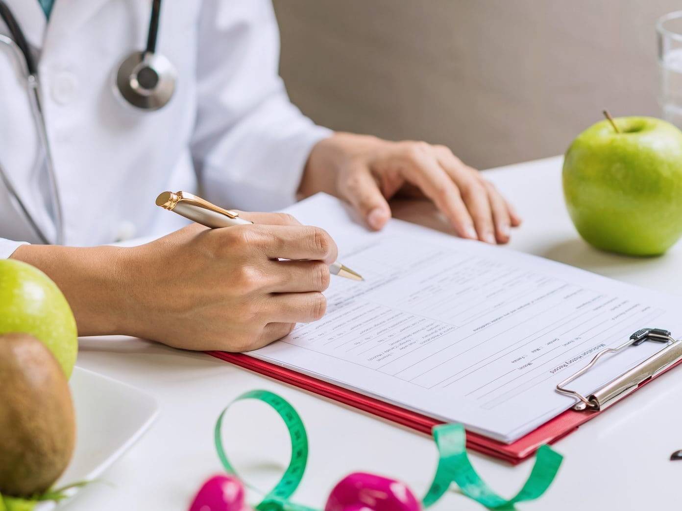 Nutritionist consulting patient on heart health with fruits and vegetables on table