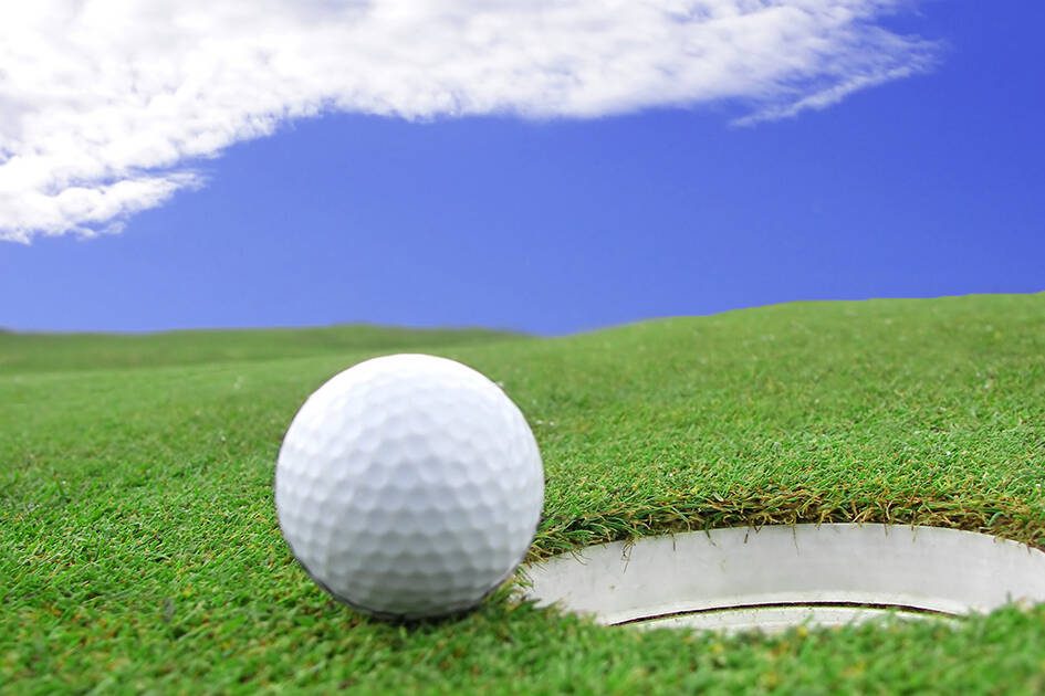Eco-Friendly Lifestyle: Close-up of a golf ball on a golf course, embodying an eco-friendly lifestyle choice, under clear skies with light clouds.