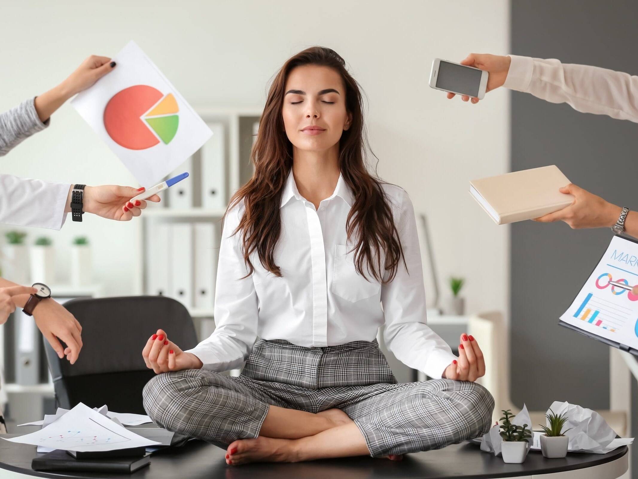 Businesswoman meditating in office to manage stress and promote heart health amidst a busy schedule.