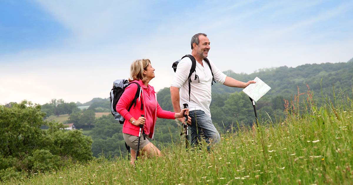 cardiovascular wellness - Happy couple walking in the park, smiling and looking well-rested on a sunny day.